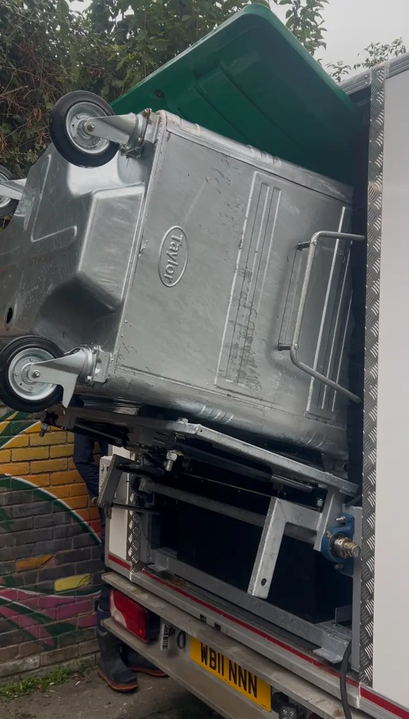Large metal commercial bin loaded on the lift at the back of the van