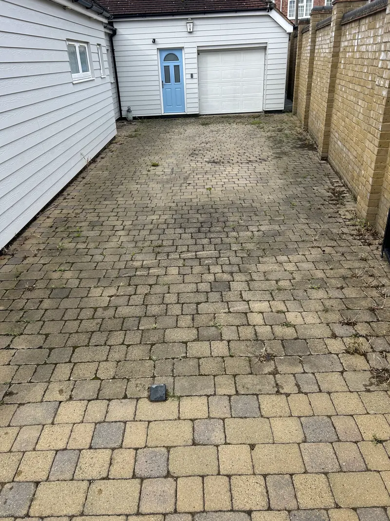 Block-paved passage between houses leading to a garage, before cleaning
