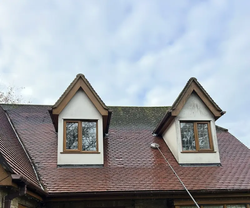 Tiled roof with two dormer windows, showing moss before cleaning