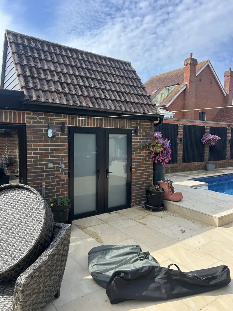 Garden room and pale stone patio beside a pool