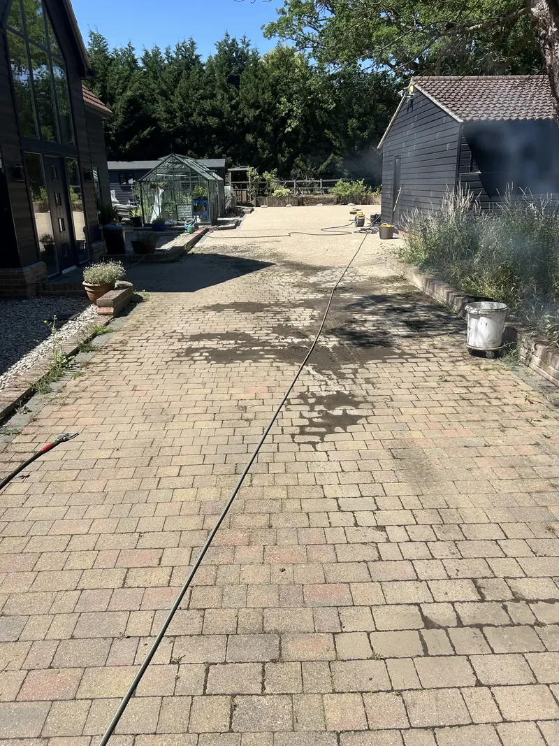 Long block-paved driveway partly cleaned, showing a clear line between clean and dirty paving