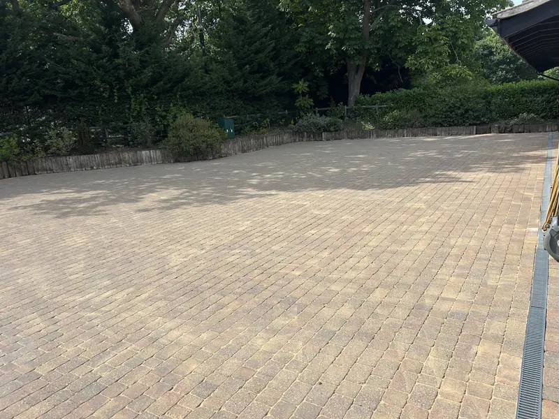 Wide block-paved driveway with a hedge behind