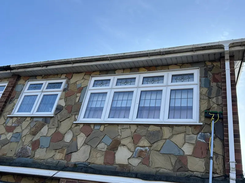 White fascia and guttering above windows on a stone-clad house