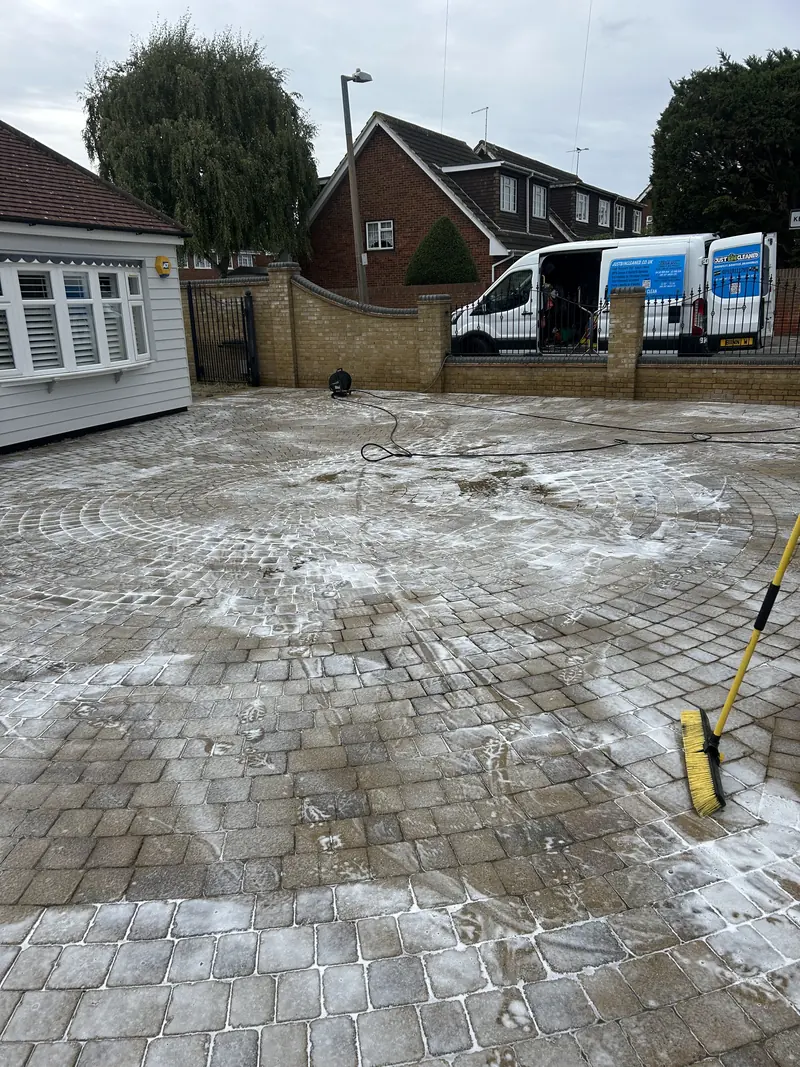 Block paving covered in cleaning foam with a brush, during a driveway clean