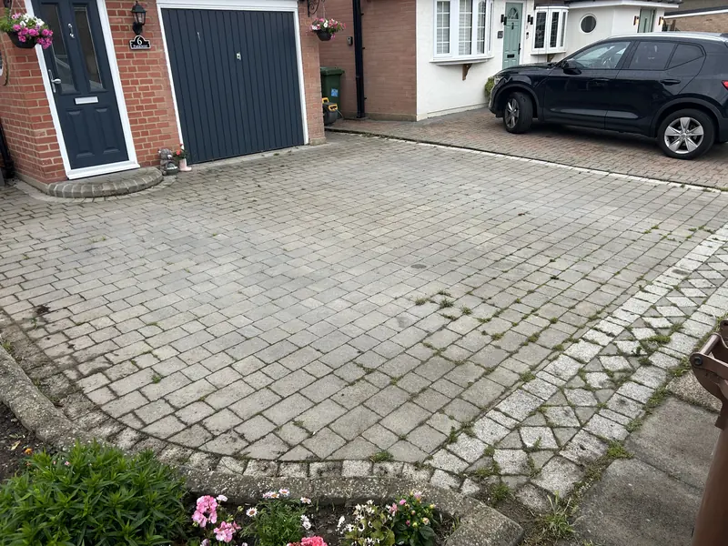 Grey block-paved driveway in front of a garage before cleaning