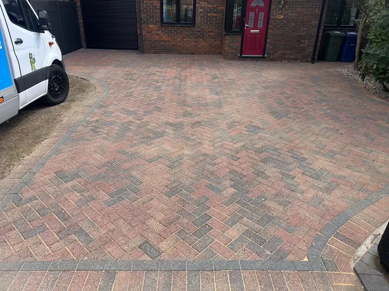 Red and grey herringbone driveway in front of a red front door