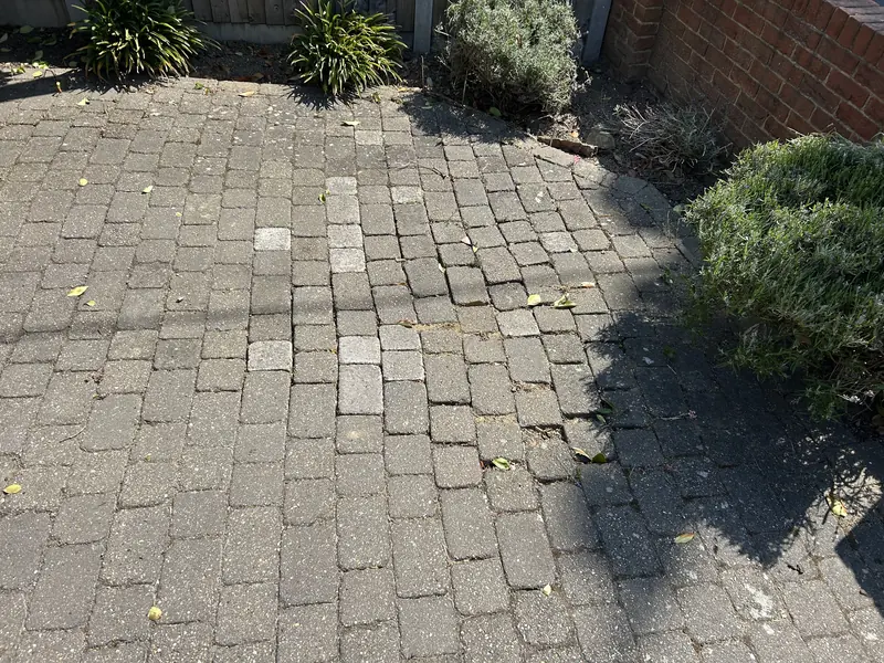 Grey block paving with loose and sunken blocks before repair