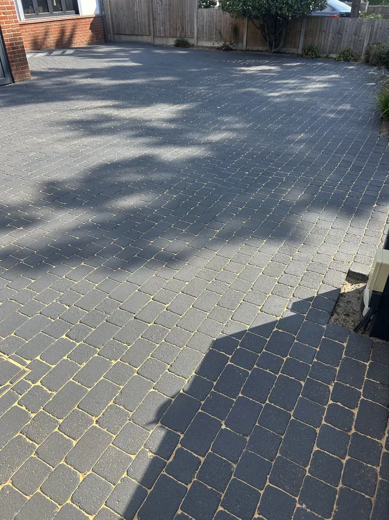 Grey block-paved driveway with fresh sand in the joints