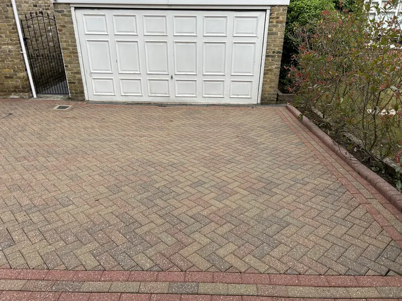 Red herringbone block paving in front of a white garage door