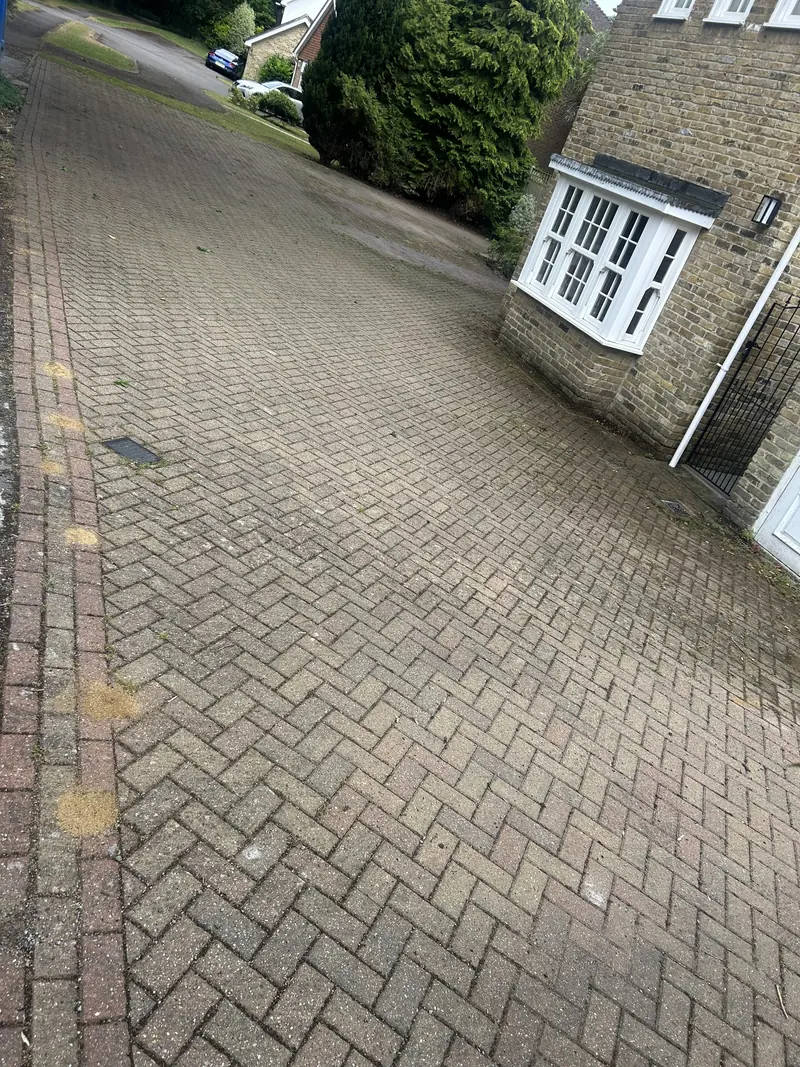 Herringbone driveway beside a house before cleaning