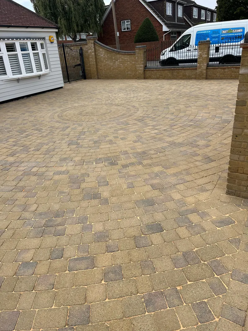 Buff block-paved drive after cleaning, with the van parked beyond the wall