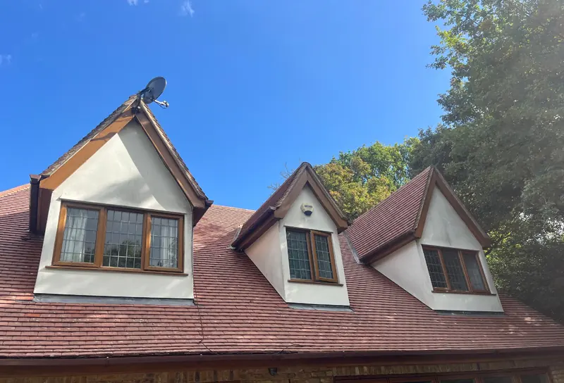 Red tiled roof with three dormer windows on a sunny day